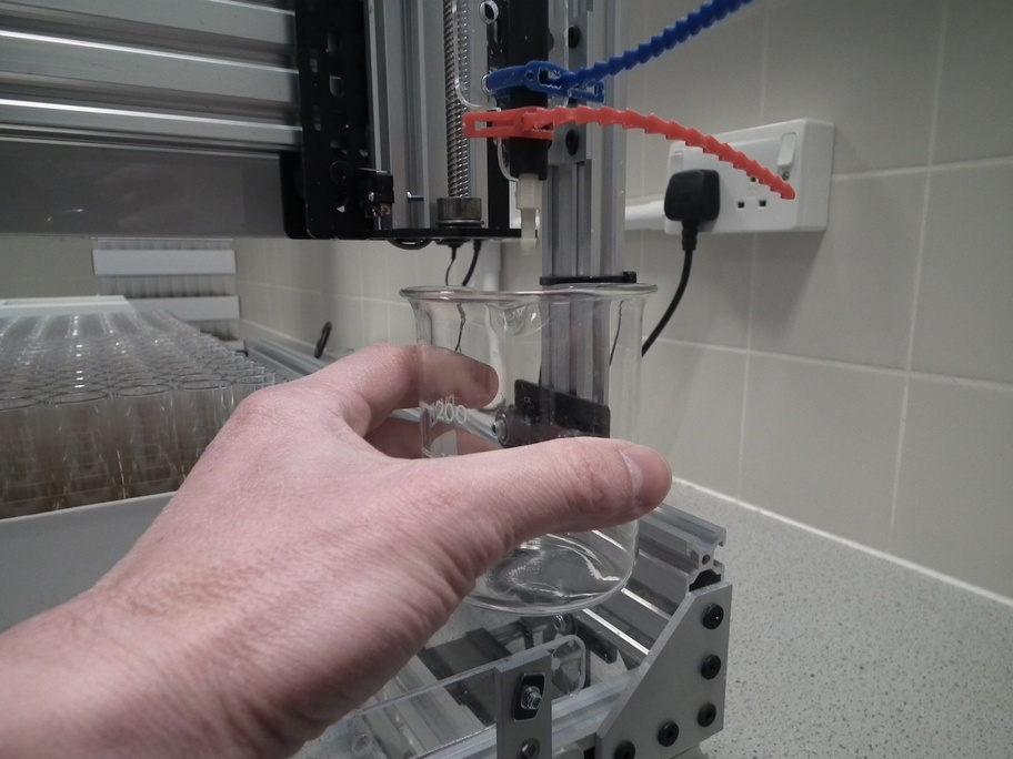Positioning of beaker under nozzle to collect fly food expelled during priming of peristaltic pump.
